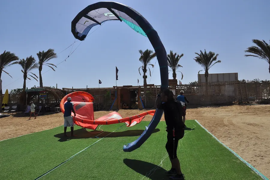 A kite resting on the grass in front of palm trees at the KiteMood beach base in Marsa Alam