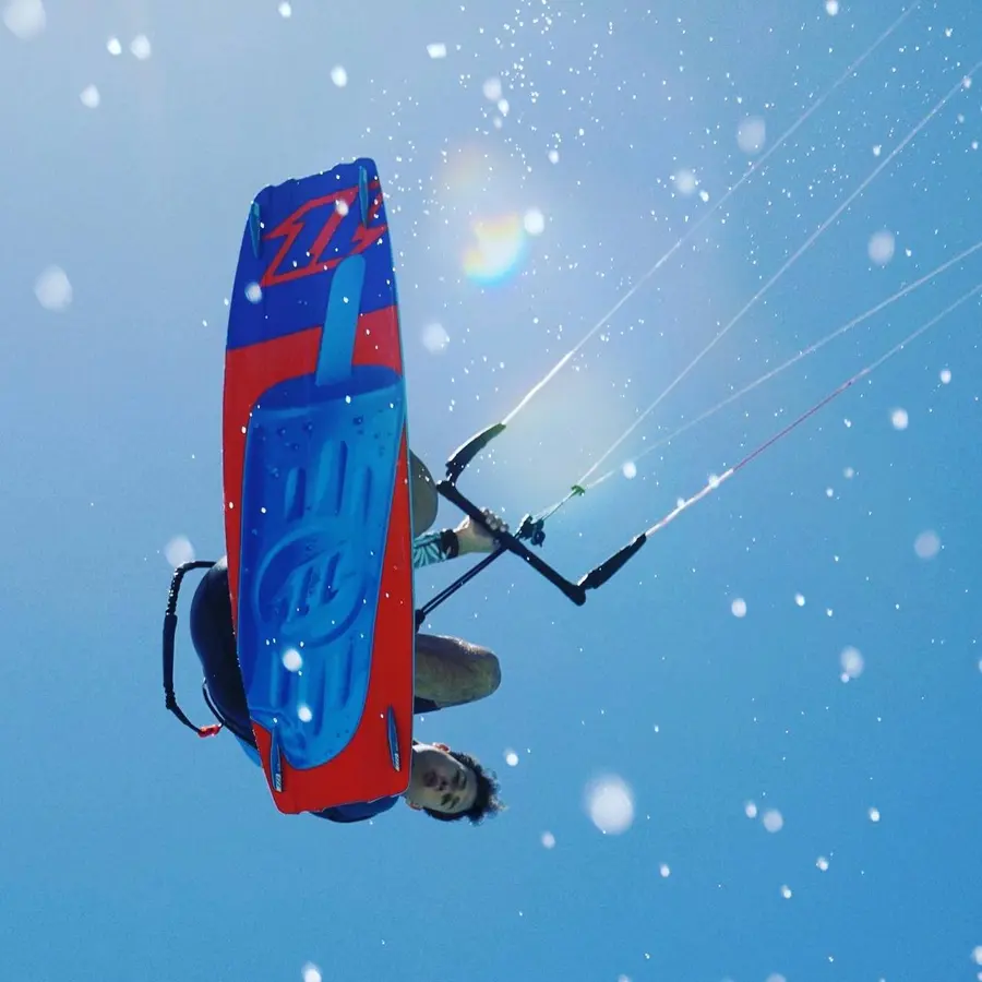 Kitesurfer jumping, photographed from below against a deep blue sky